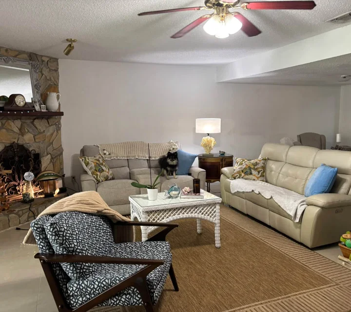 A welcoming living room with cream sofas and a stone fireplace